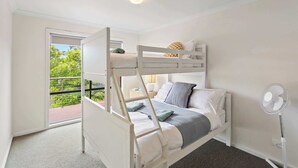 Dormitorio con literas, ventana y vista a zonas verdes.