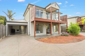 Ein zweistöckiges Haus mit Garage, überdachter Veranda und einem angelegten Garten.