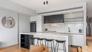 Una cocina moderna con una isla central, taburetes de bar y un sofá en la sala de estar.