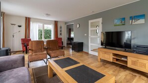 A spacious living room with a large TV, comfortable seating, and a wooden entertainment unit. - Villa With Finnish Sauna and Outdoor Shower (De Koog)