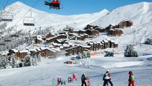 A ski resort with multiple wooden lodges, ski lifts, and a snowy landscape. - Apartment in Belle Plagne on Ski Slopes (La Plagne-Tarentaise)