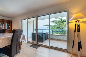 A modern room with a dining table, chairs, a sofa, and a lamp. - View of the Entrance to the Gulf of Morbihan (Arzon)
