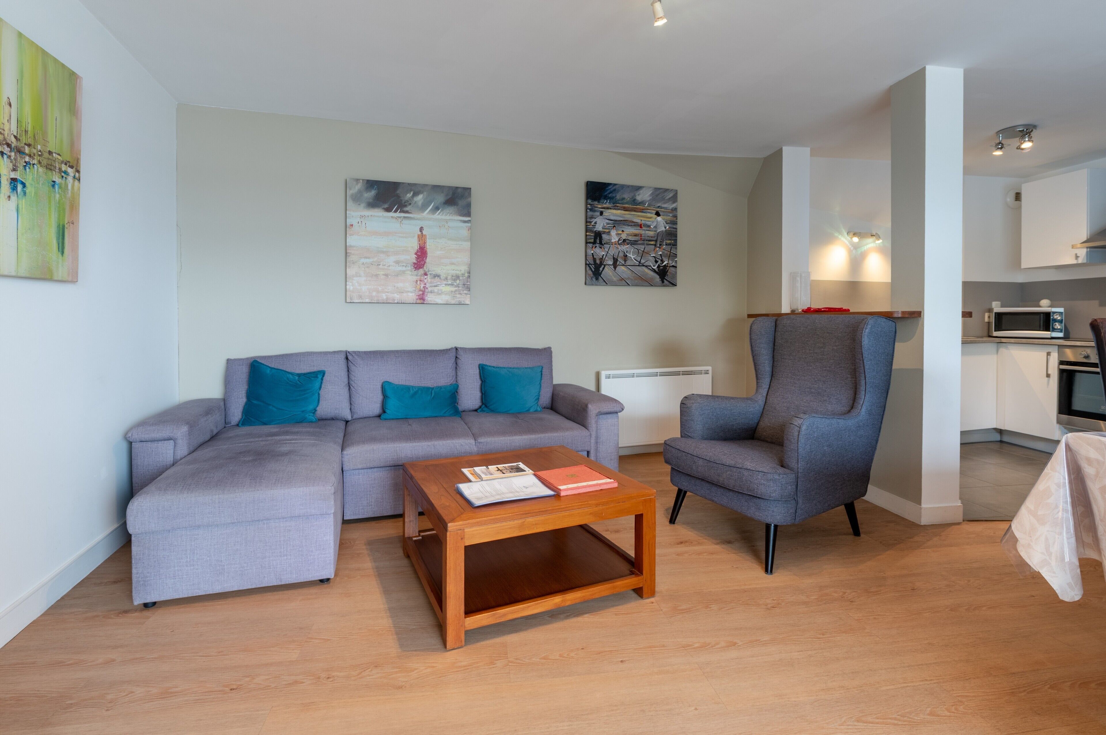 Ein modernes Wohnzimmer mit einem grauen Sofa, einem Holztisch und einem grauen Sessel.
