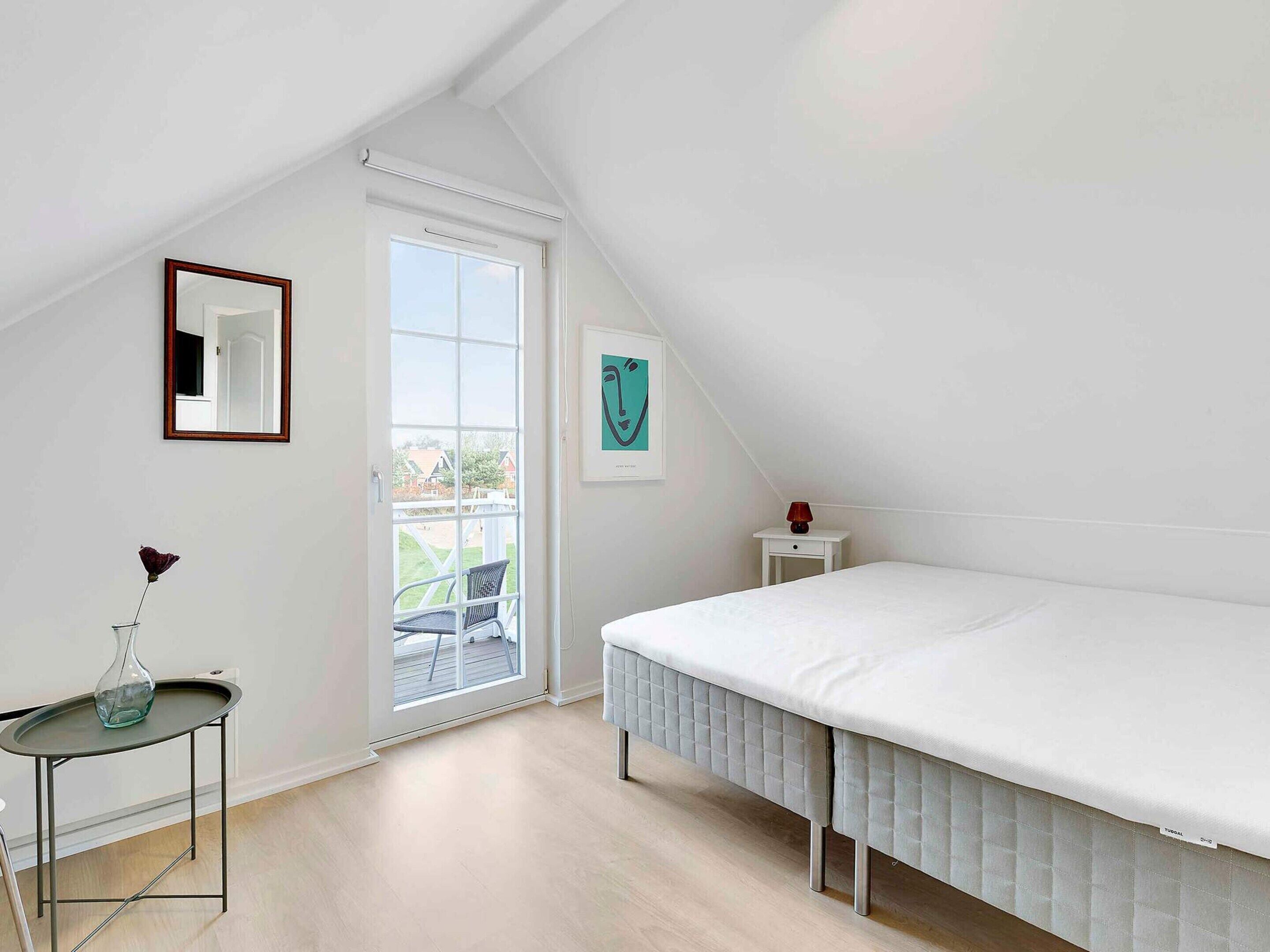 Ein Schlafzimmer mit Bett, Nachttisch, Stuhl, Fenster und Tür.