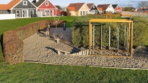 Ein Spielplatz mit Sportgeräten, einer Holzschaukel und einem Sandbereich.