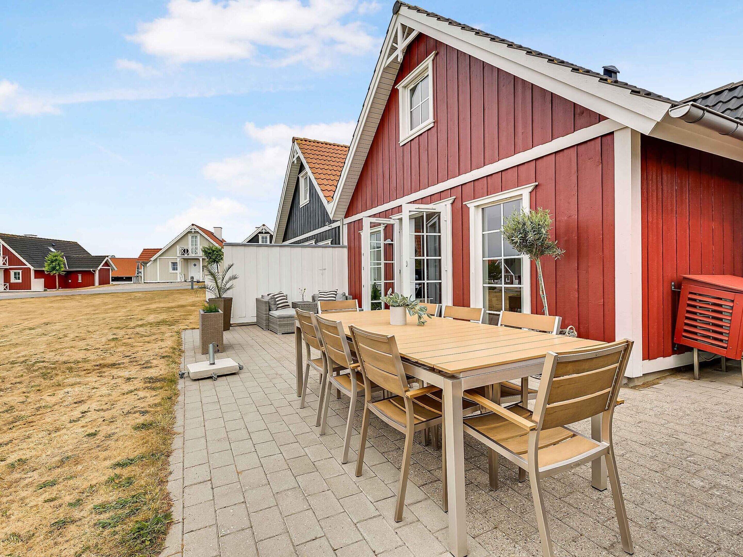 A red house with a tiled patio and a wooden table with chairs.