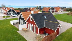 Ein rotes Haus mit schwarzem Dach, einer überdachten Veranda und einem kleinen Schuppen.