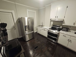 A kitchen with stainless steel appliances, white cabinets, and a dark wooden floor. - 2BR Apartment Near Wesleyan 102 (Middletown)