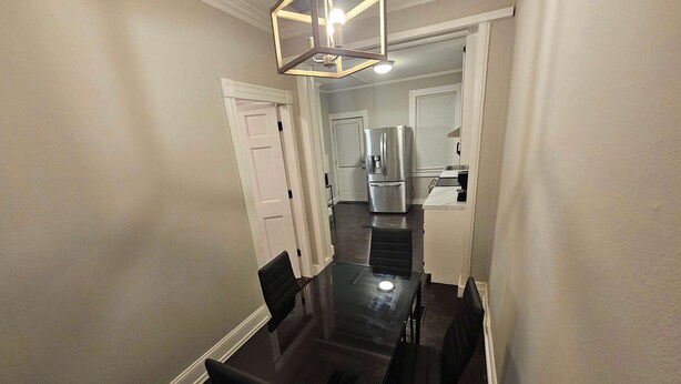 A compact kitchen with modern appliances, a dining area with a glass table and black chairs, and a geometric pendant light. - 2BR Apartment Near Wesleyan 102 (Middletown)
