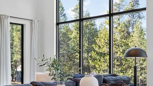 A modern living room with a large window, a wooden coffee table, and a sofa.