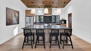 A modern kitchen with a large island, bar stools, and pendant lighting.