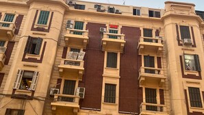 A multi-story building with balconies, air conditioning units, and a red sign on the facade. - New Pharoah's Palace hotel (Cairo)