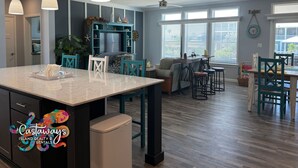 A spacious kitchen with a large island, teal chairs, and a dining area with a table and chairs. - Blue Heron is your waterfront 3BR/2BA getaway with boat lift, huge seawall (St James City)