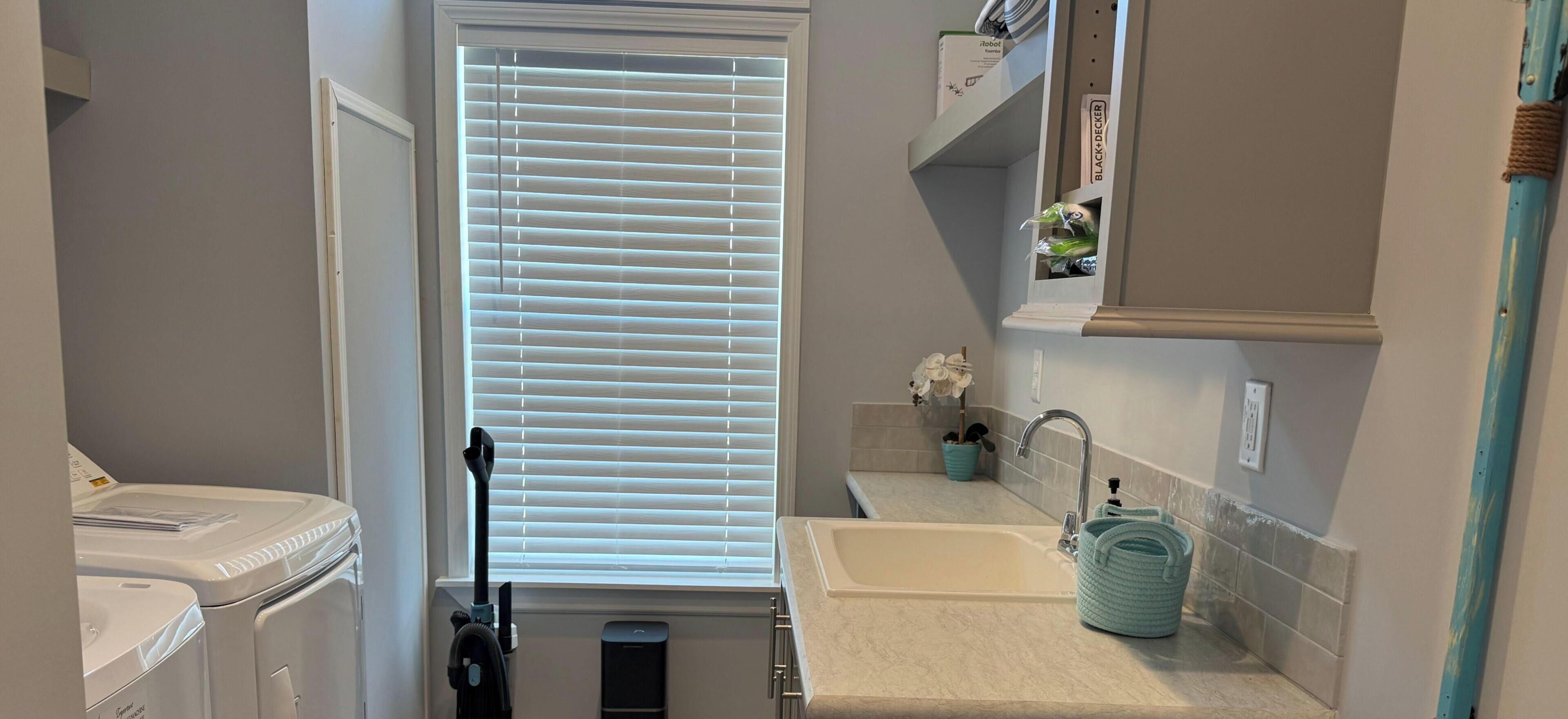 A compact kitchen with a washing machine, a vacuum cleaner, and a sink.