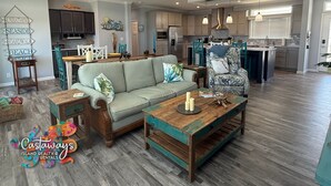 A spacious living room with a sofa, coffee table, and a dining area with chairs. - Blue Heron is your waterfront 3BR/2BA getaway with boat lift, huge seawall (St James City)