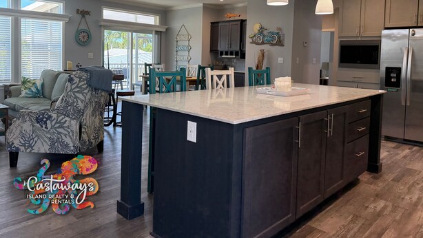 A modern kitchen with dark cabinets, stainless steel appliances, and a large island. - Blue Heron is your waterfront 3BR/2BA getaway with boat lift, huge seawall (St James City)