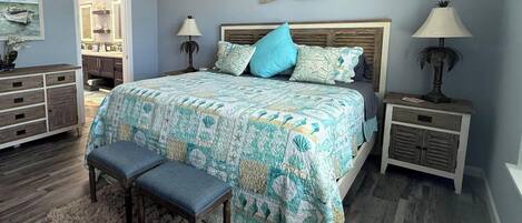 A bedroom with a bed, two nightstands, a bench, a dresser, and a mirror.