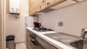 Een kleine keuken met een gasfornuis, een spoelbak en houten kastjes.