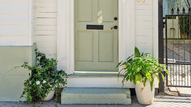 A white house with the number 83 on the front door, two lanterns, and a potted plant in front. - Luxe 5BR w/ Heated Pool~1 Block to King~Lowcountry House (Charleston)