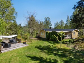 A two-story house with a deck, surrounded by trees and a grassy yard. - 4 Star Holiday Home in Bergshamra (Bergshamra)