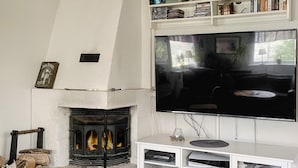 A living room with a fireplace, a flat-screen TV mounted on the wall, and a white entertainment unit with electronic devices. - 4 Star Holiday Home in Bergshamra (Bergshamra)