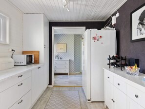 A compact kitchen with white cabinets, a microwave, and a refrigerator. - 4 Star Holiday Home in Bergshamra (Bergshamra)