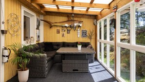 A cozy room with a wooden ceiling, a large window, a sofa, a table, and a potted plant. - 4 Star Holiday Home in Bergshamra (Bergshamra)