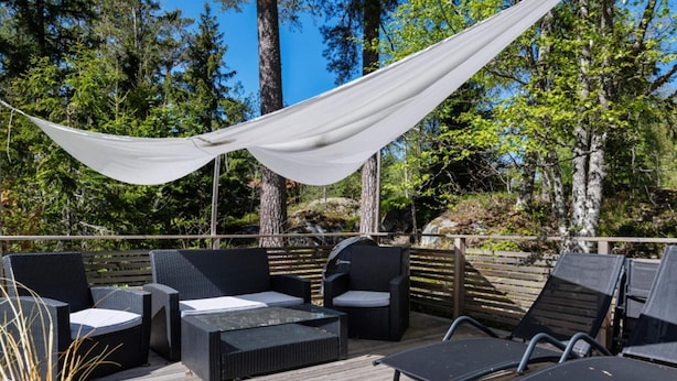An outdoor deck with wicker furniture, a grill, and a canopy. - 4 Star Holiday Home in Bergshamra (Bergshamra)