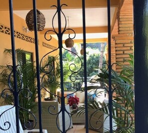 Ein Balkon mit schmiedeeisernen Geländern, Pflanzkübeln und Blick auf einen Garten.