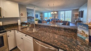 Eine moderne Küche mit Granit Arbeitsplatten, Edelstahlgeräten und einem Essbereich mit einem Glastisch und Stühlen.