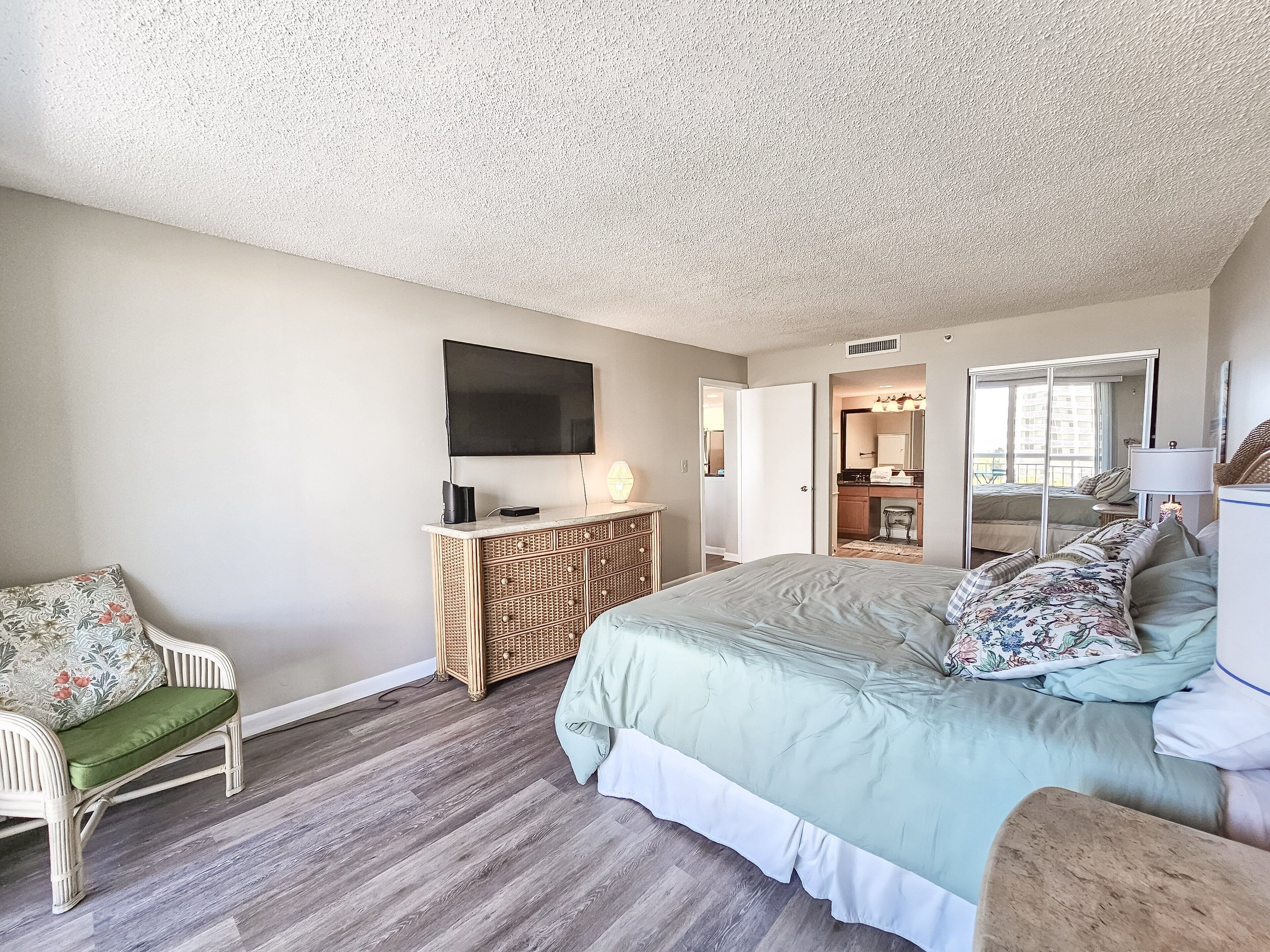 A bedroom with a large bed, a television, a dresser, and a chair.