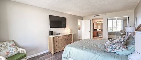 A bedroom with a large bed, a television, a dresser, and a chair.