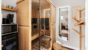 A modern room with a sauna, a coffee machine, a refrigerator, and a mirror.