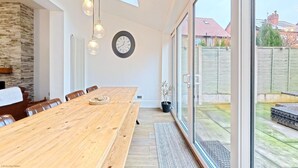 Ein geräumiger Essbereich mit einem Holztisch, Stühlen und einer Uhr an der Wand.