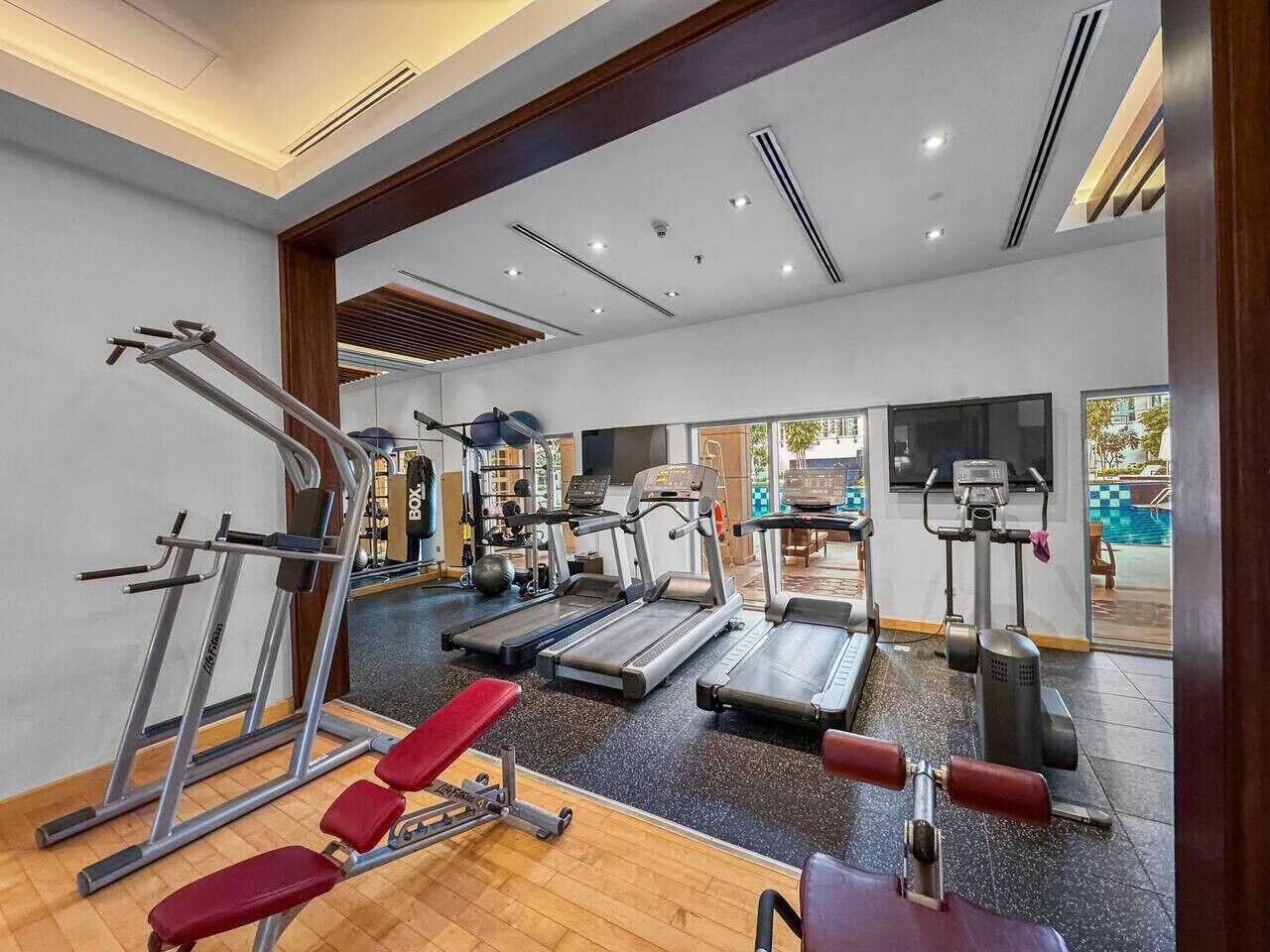 Et fitnesscenter med løbebånd, styrkemaskiner og en rød bænk.