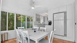 A modern kitchen with white cabinetry, a built-in refrigerator, and a dining area with white chairs and a table. - Charming 2-bedroom bungalow in lovely Delray Beach with AC (Delray Beach)