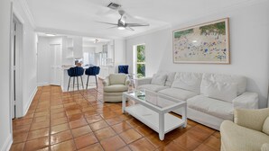 A spacious living room with a white sofa, a coffee table, and a painting on the wall. - Charming 2-bedroom bungalow in lovely Delray Beach with AC (Delray Beach)