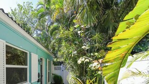 A narrow brick pathway leading to a turquoise building with white shutters and a white picket fence. - Charming 2-bedroom bungalow in lovely Delray Beach with AC (Delray Beach)