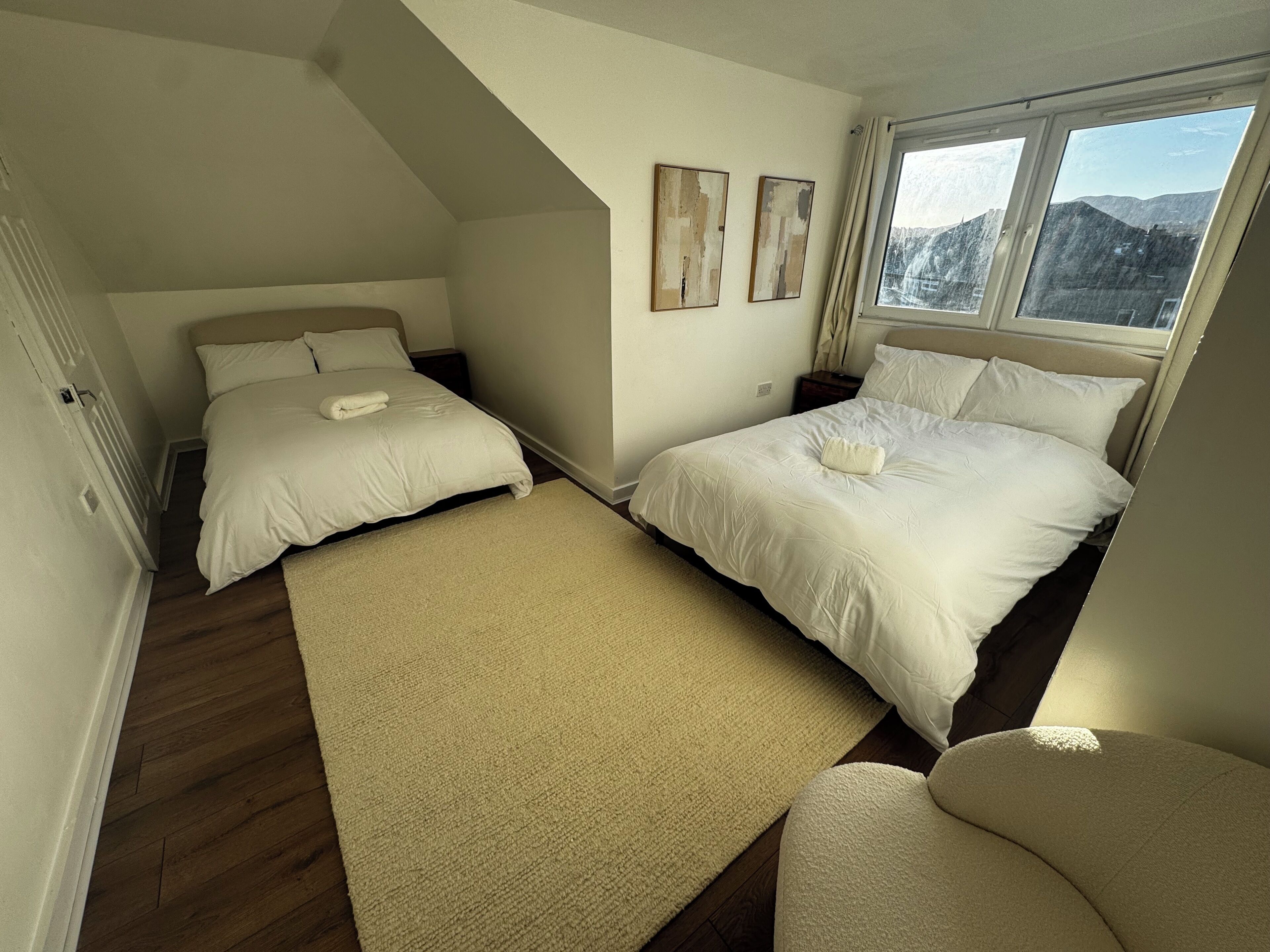 Un dormitorio con dos camas, un ventanal y vistas a las montañas.