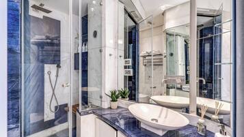 Un baño moderno con ducha de vidrio, encimera de mármol y un espejo grande.