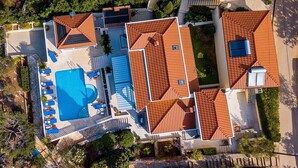 Vue aérienne d’une propriété comprenant une piscine, plusieurs bâtiments et un espace vert environnant.