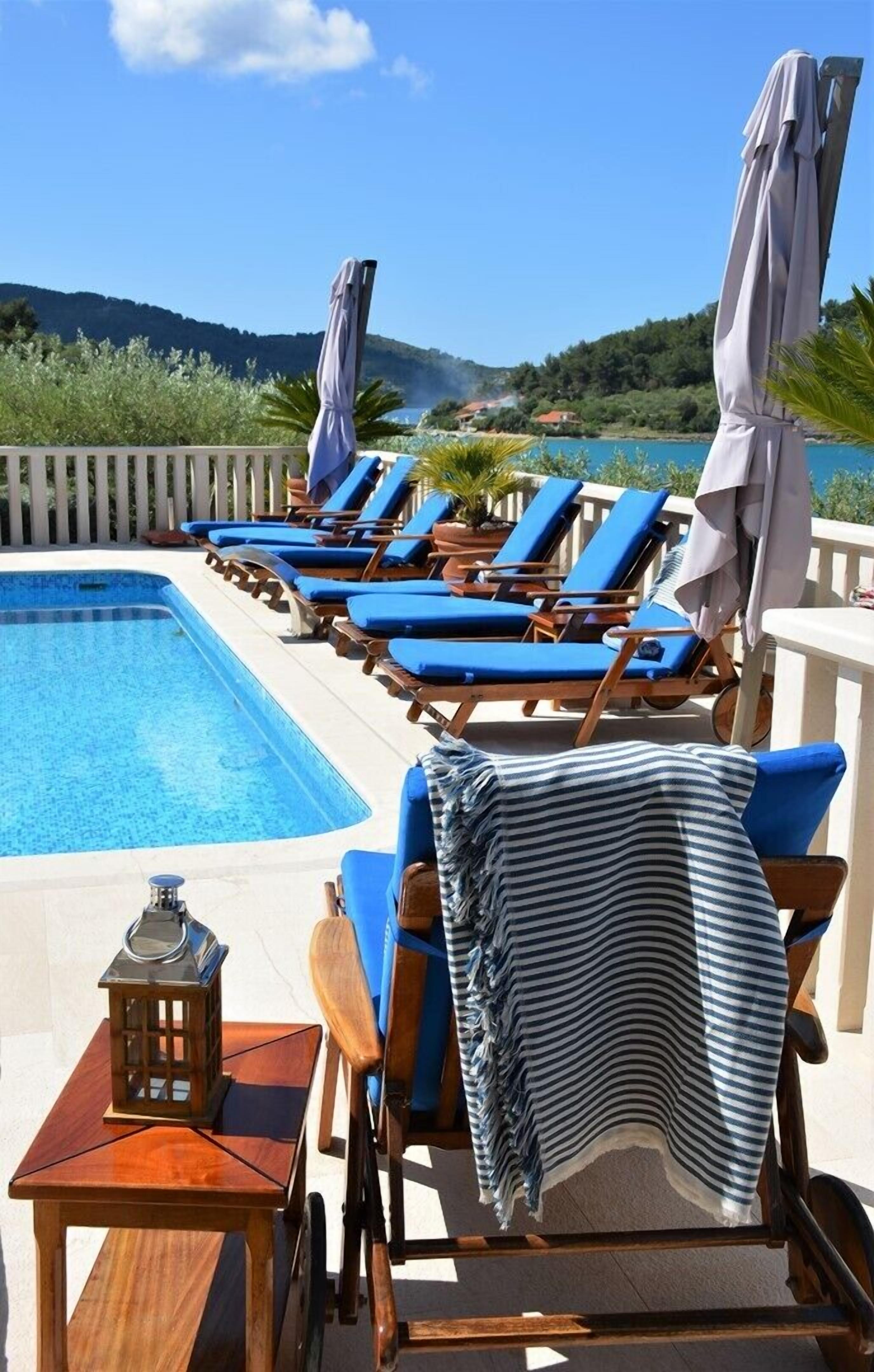A poolside area with lounge chairs, a table, and a lantern.