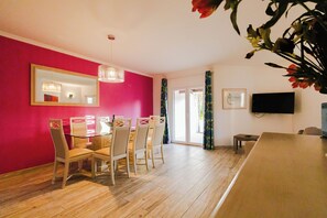 A dining area with a table and chairs, a large mirror, and a television on the wall.