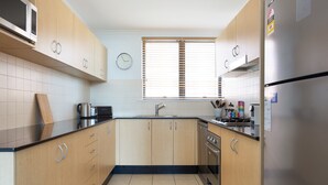 A kitchen with wooden cabinets, a stainless steel refrigerator, a microwave, and a stove. - Chic Unit With Rooftop Terrace Near Sights & Shops (Sydney)