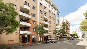A multi-story building with balconies, a bicycle parked outside, and a car on the street. - Chic Unit With Rooftop Terrace Near Sights & Shops (Sydney)