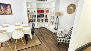 Un salon moderne comprenant un coin repas, une bibliothèque et un ventilateur de plafond.