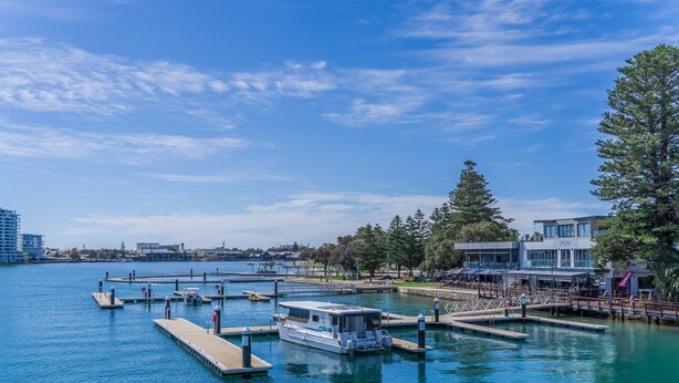 A marina with boats docked, a pier, and buildings in the background. - 3 bedroom Villa walking distance to Mandurah foreshore (Mandurah)