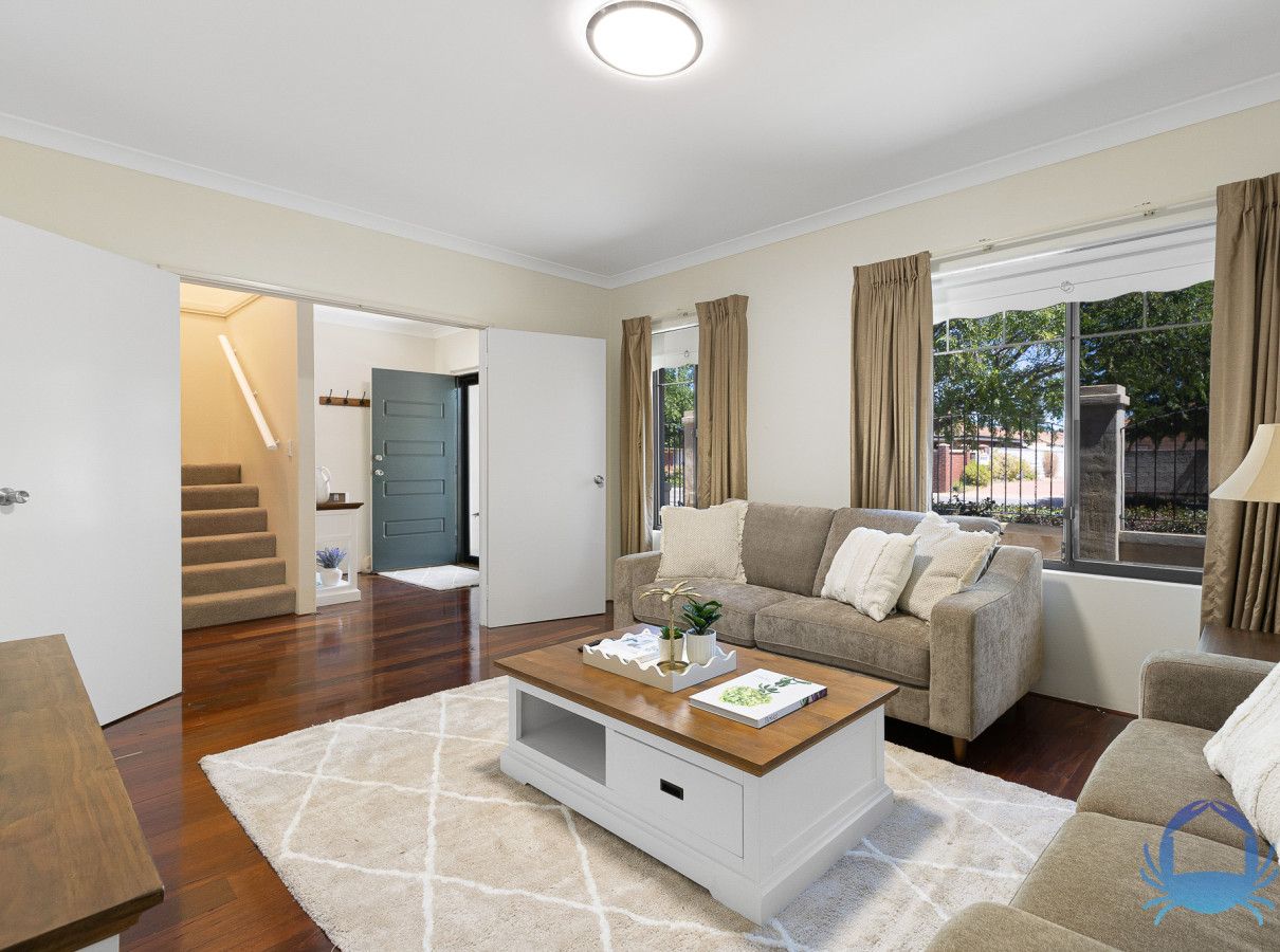 A spacious living room with a beige sofa, a wooden coffee table, and a view of the outdoors through large windows.