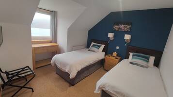 A room with two beds, a desk, and a chair.