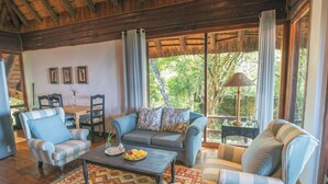 A cozy living room with a sofa, armchairs, a coffee table, and a dining area with a table and chairs. - Sobhengu Lodge by Dream Resorts (KwaNibela)